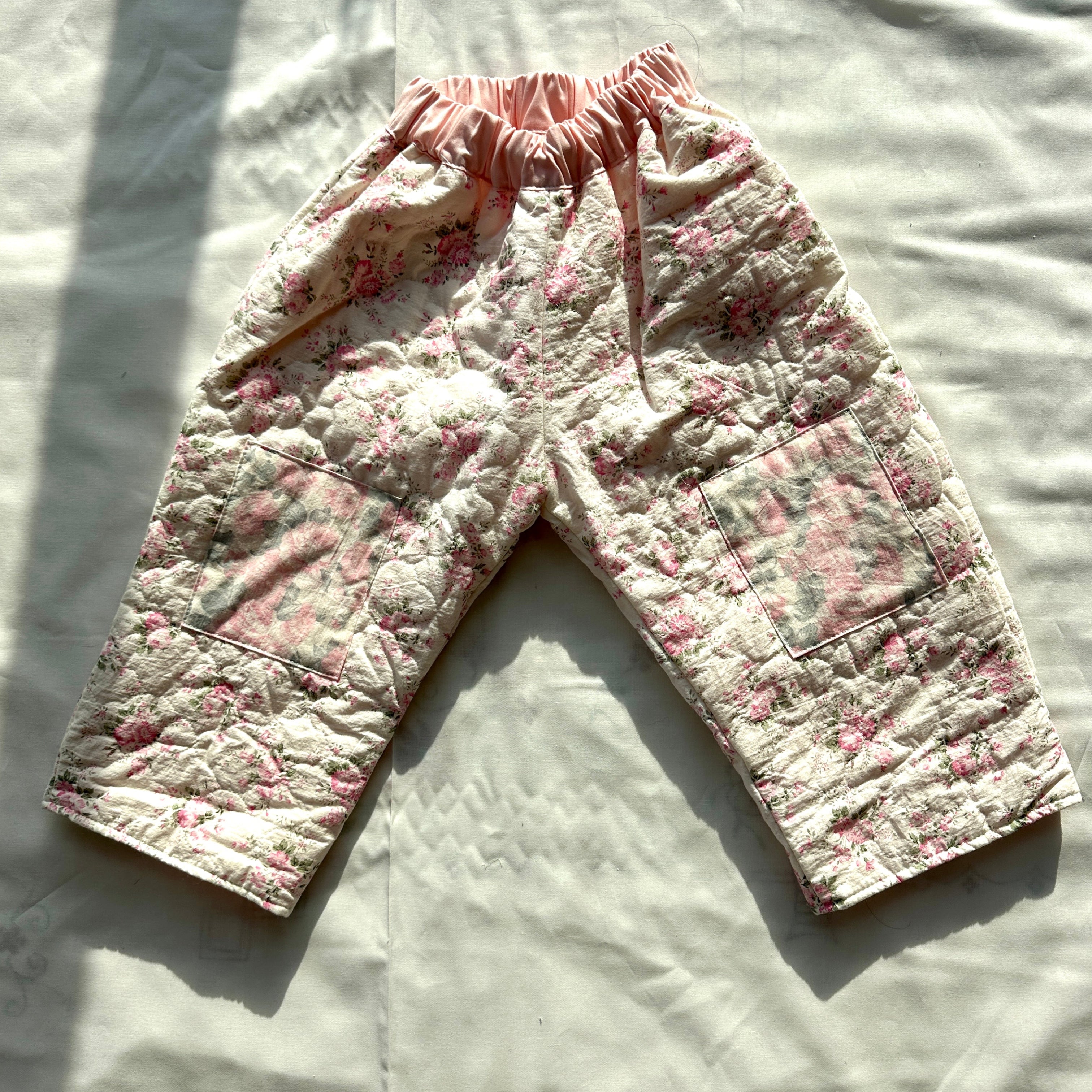 Floral-patterned baby pants on a light fabric background